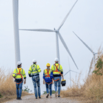 4 wind turbine technicians walking down a path to work on wind turbine