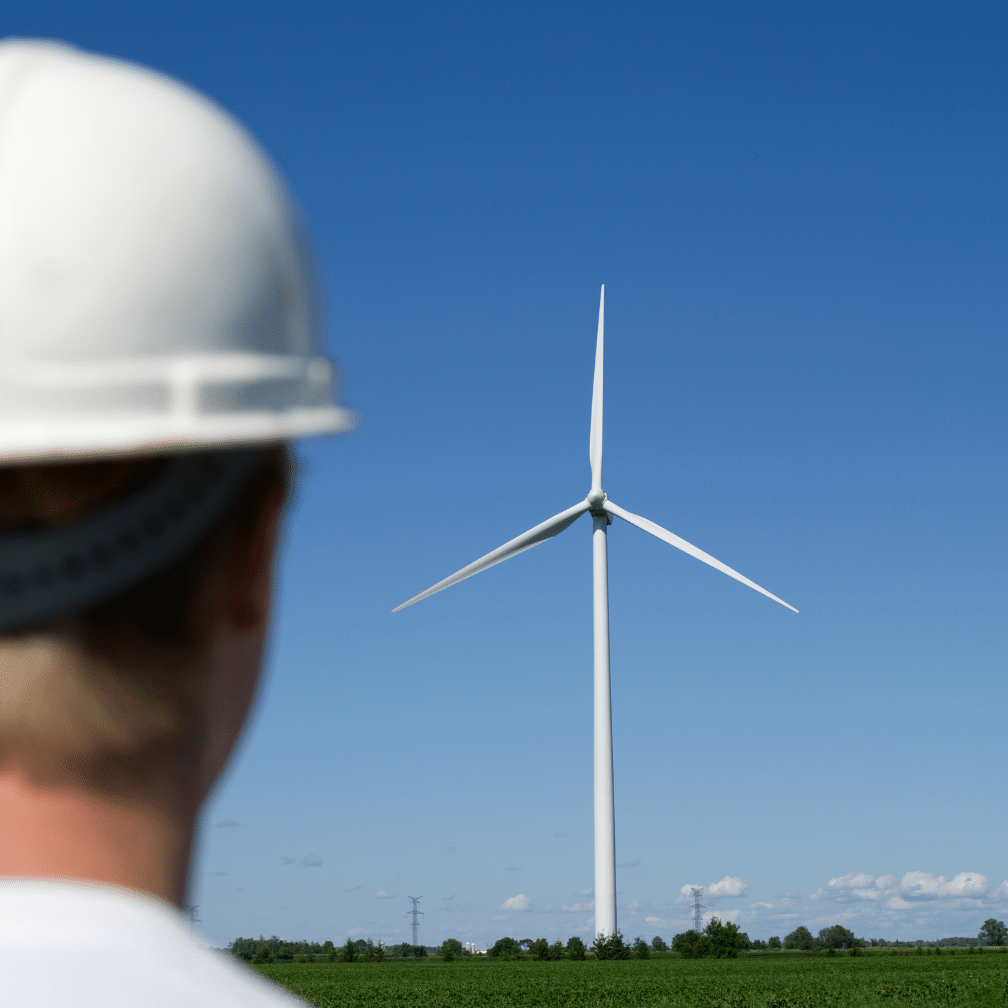 Back of head of Man looking at a built wind turbine in the distance.