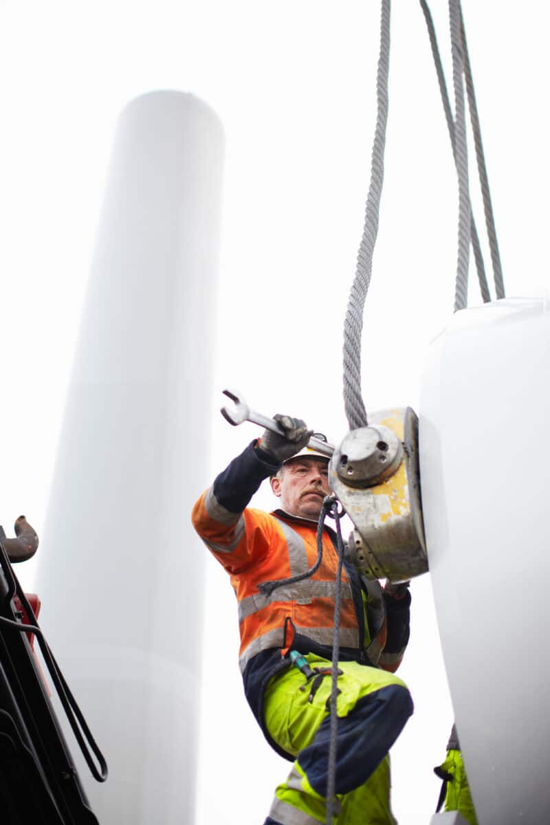 a man wearing a hard hat and protective gear during maintenance on a wind turbine