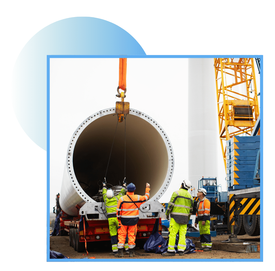 Workers assembling a wind turbine base with crane and heavy equipment
