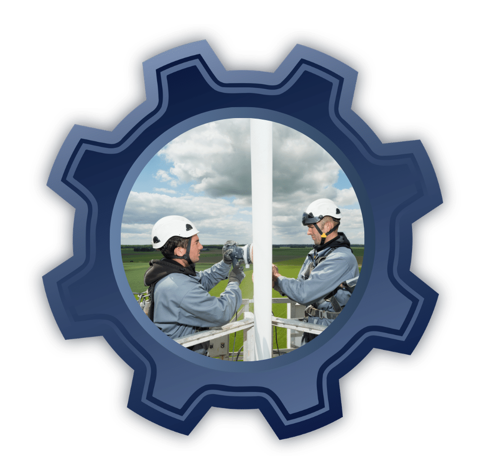 Two technicians in hard hats secure a tall pole on an outdoor wind turbine installation site.